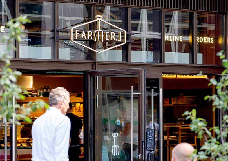 Farmer J signage is pictured on the glass
frontage and people walking by. 